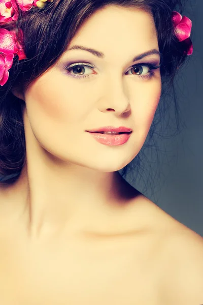 Retrato de bela morena sexual com orquídeas rosa nos cabelos. emoções, cosméticos — Fotografia de Stock