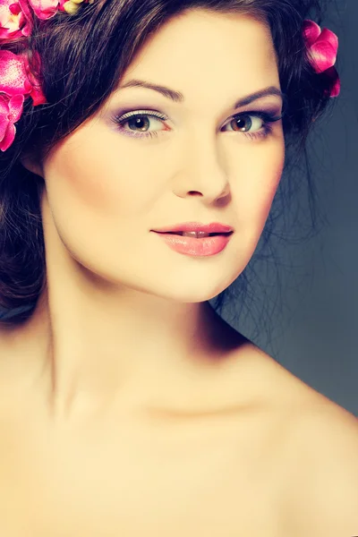 Retrato de hermosa morena sexual con orquídeas rosadas en pelos. emociones, cosméticos —  Fotos de Stock