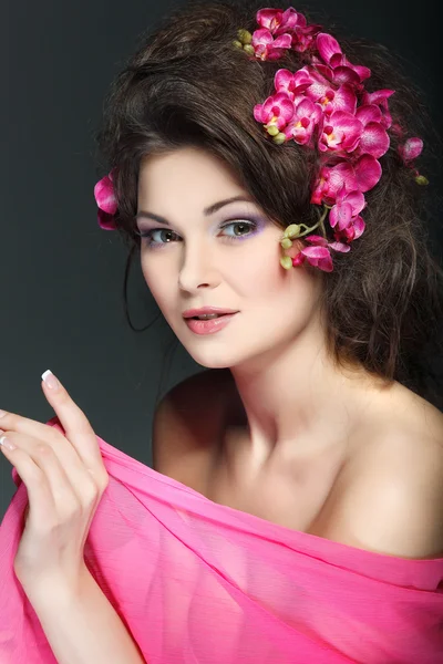 Retrato de bela morena sexual com orquídeas rosa nos cabelos. emoções, cosméticos — Fotografia de Stock