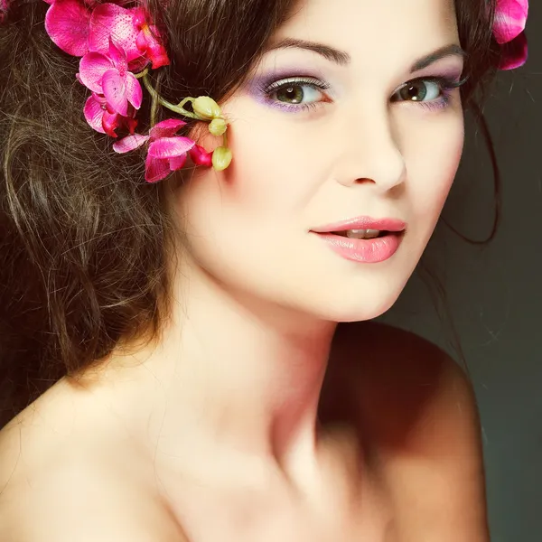 Porträtt av vackra sexuella brunett med rosa orkidéer i hårstrån. känslor, kosmetika — Stockfoto