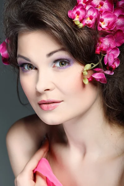 Porträt der schönen sexuellen Brünette mit rosa Orchideen im Haar. Emotionen, Kosmetik — Stockfoto