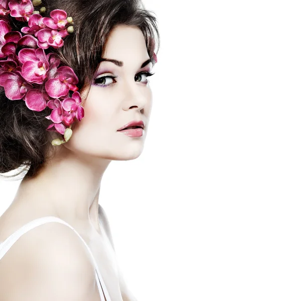 Portrait of beautiful sexual brunette with pink orchids in hairs. emotions, cosmetics — Stock Photo, Image