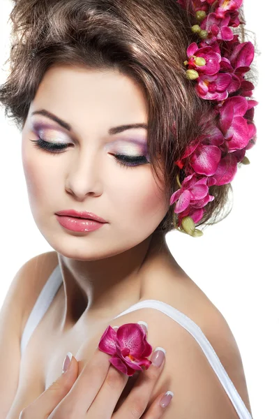 Portrait of beautiful sexual brunette with pink orchids in hairs. emotions, cosmetics Stock Picture