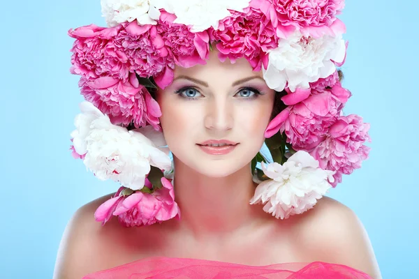 Hermosa joven con flores de color rosa sobre un fondo azul — Foto de Stock