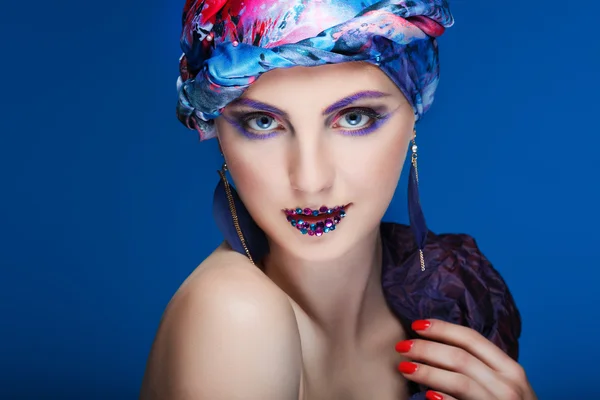 Uma foto de menina bonita em um vestido de cabeça do tecido colorido, em um fundo azul, glamour — Fotografia de Stock