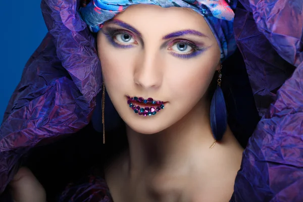 Uma foto de menina bonita em um vestido de cabeça do tecido colorido, em um fundo azul, glamour — Fotografia de Stock