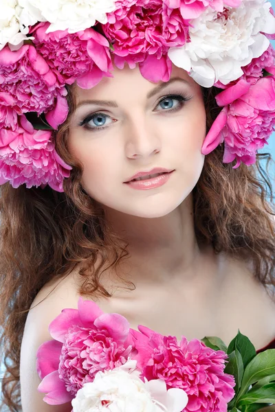 Belle jeune fille avec des fleurs roses sur un fond bleu — Photo