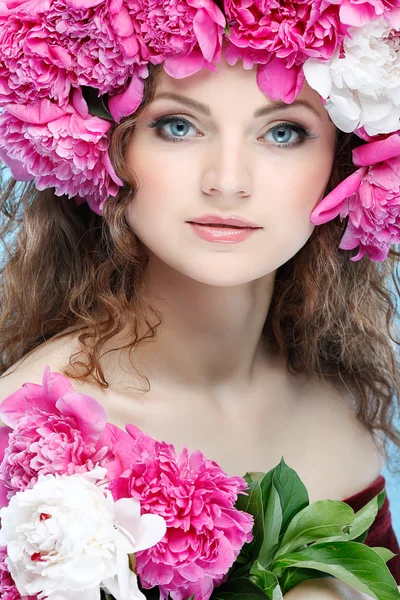 Hermosa joven con flores de color rosa sobre un fondo azul — Foto de Stock