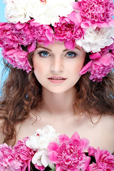 Belle jeune fille avec des fleurs roses sur un fond bleu — Photo