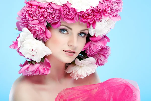 Hermosa joven con flores de color rosa sobre un fondo azul —  Fotos de Stock