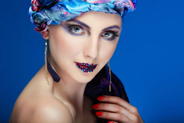 Uma foto de menina bonita em um vestido de cabeça do tecido colorido, em um fundo azul, glamour — Fotografia de Stock