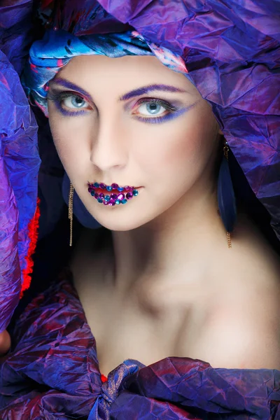 Uma foto de menina bonita em um vestido de cabeça do tecido colorido, em um fundo azul, glamour — Fotografia de Stock