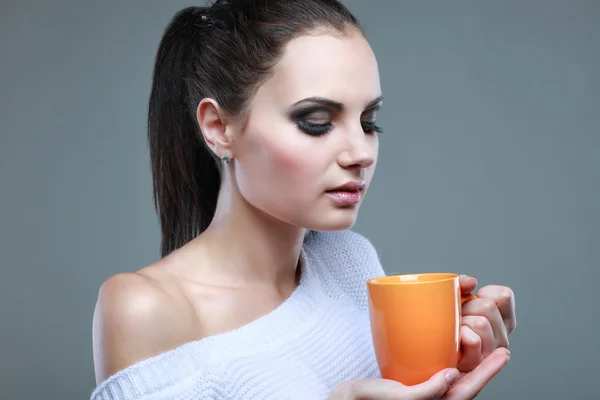 Mooi meisje met de kop van thee op grijze achtergrond — Stockfoto