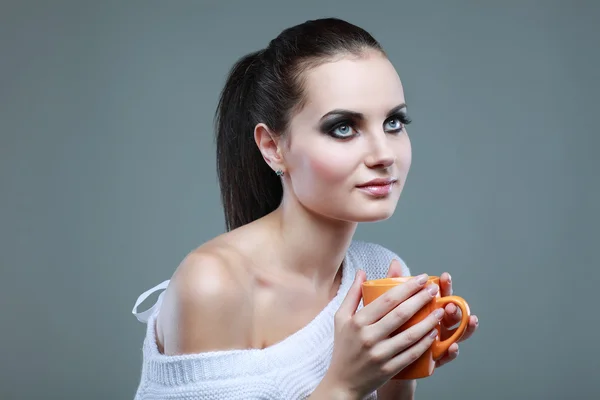 Hermosa joven con la taza de té sobre fondo gris — Foto de Stock