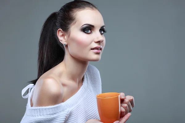 Hermosa joven con la taza de té sobre fondo gris — Foto de Stock