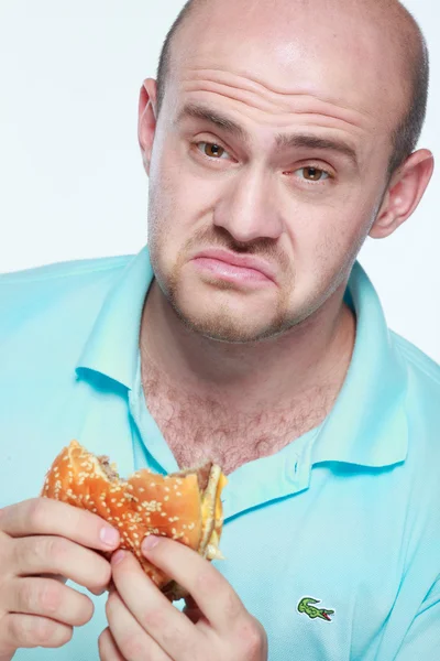 Funny man eating hamburger on grey background — Stock Photo, Image