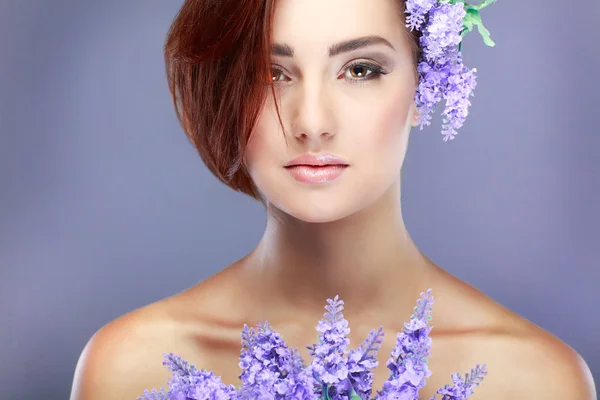Close-up portrait of beautiful young girl with violet flowers — Stock Photo, Image