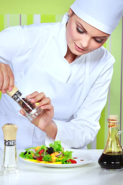 Schöne junge Köchin bereitet und dekoriert leckeres Essen in der Küche — Stockfoto