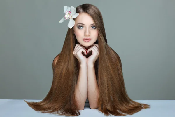 El retrato de la muchacha hermosa con los cabellos largos con la orquídea en el peinado — Foto de Stock