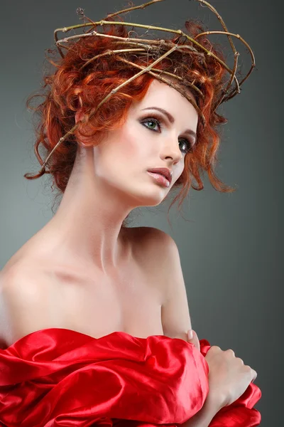 Rode haren. Portret van mooi meisje in rode stof in een chaplet uit takken. — Stockfoto