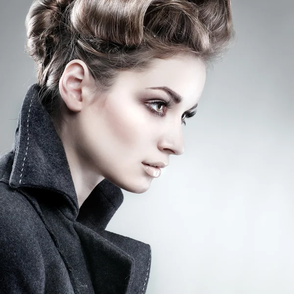 Portrait de jeune femme élégante en manteau gris sur fond gris — Photo