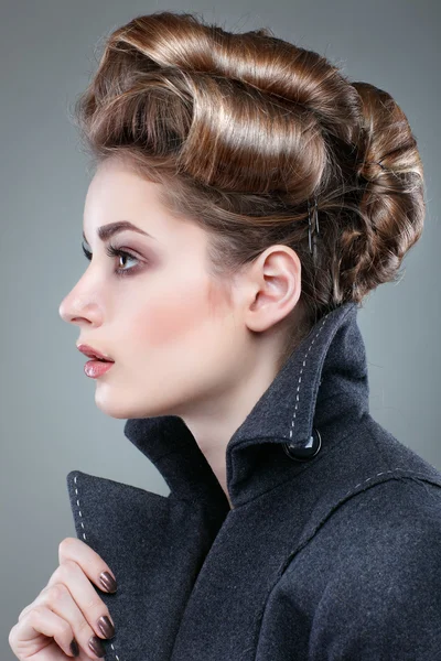 Retrato de uma jovem elegante com um sobretudo cinzento sobre fundo cinzento — Fotografia de Stock