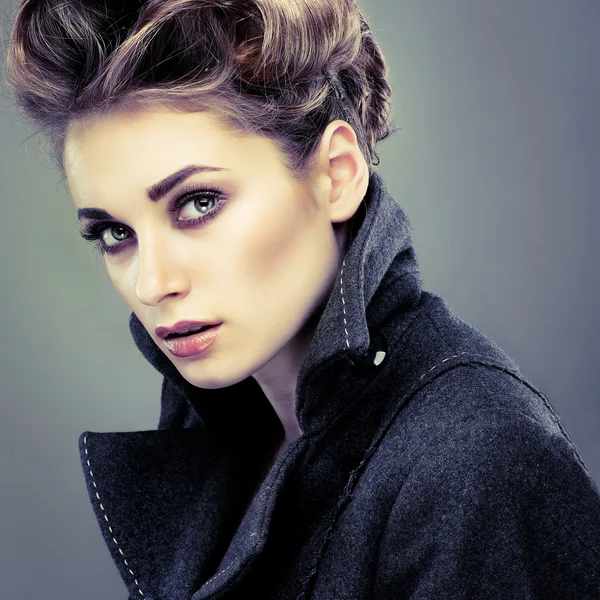 Portrait de jeune femme élégante en manteau gris sur fond gris — Photo