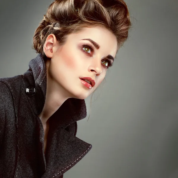 Portrait of elegant young woman in a grey overcoat on a grey background — Stock Photo, Image