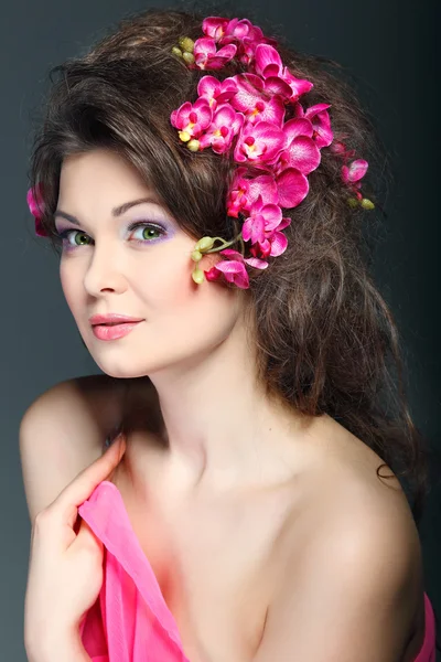 Portret van prachtige seksuele brunette met roze orchideeën in haren. emoties, cosmetica — Stockfoto