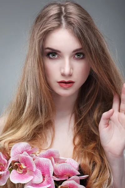 Schönes Mädchen, isoliert auf einem hellgrauen Hintergrund mit rosa Orchideen, Emotionen, Kosmetik — Stockfoto