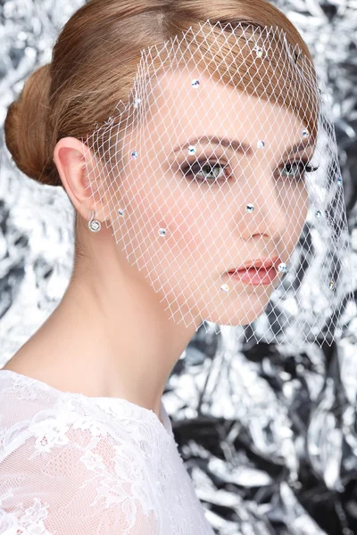 Bella ragazza con la testa bianca in un velo su uno sfondo argenteo, emozioni, cosmetici — Foto Stock