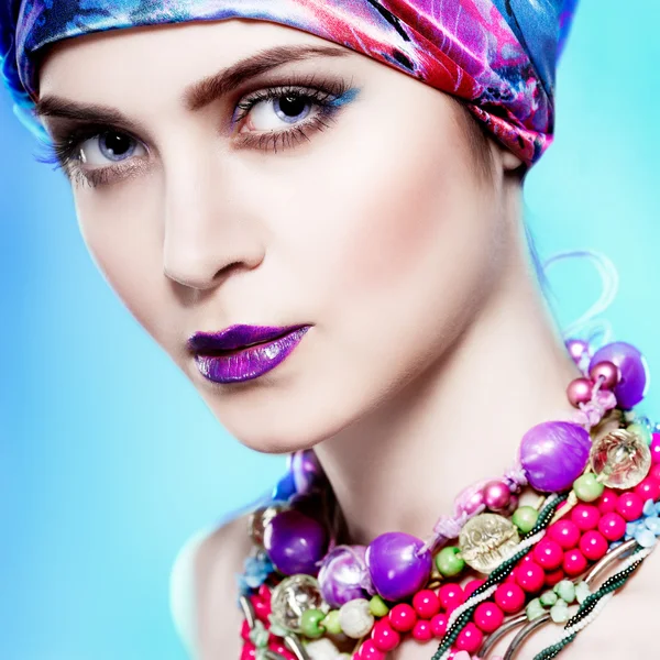 Una foto de una hermosa chica en un vestido de cabeza de la tela de color, sobre un fondo azul, glamour — Foto de Stock