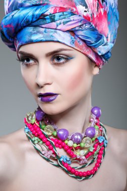 gri bir arka planda glamour renkli kumaştan bir kafa elbiseli güzel kız fotoğrafı