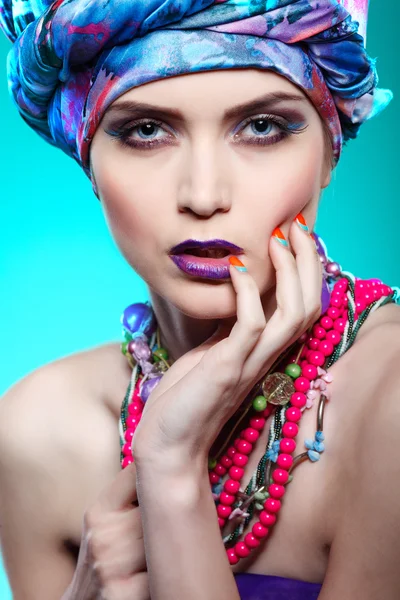 Una foto de una hermosa chica en un vestido de cabeza de la tela de color, sobre un fondo azul, glamour —  Fotos de Stock