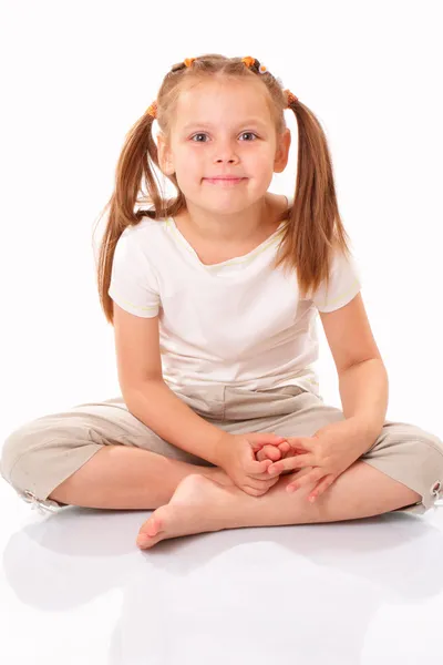 Красивая маленькая девочка сидит и улыбается — стоковое фото