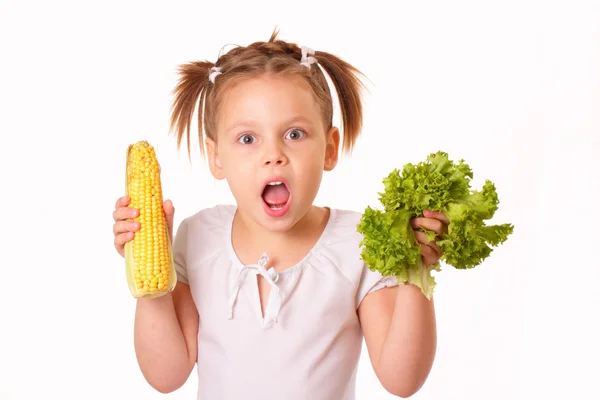 Забавная маленькая девочка с кукурузой и салатом в руках — стоковое фото
