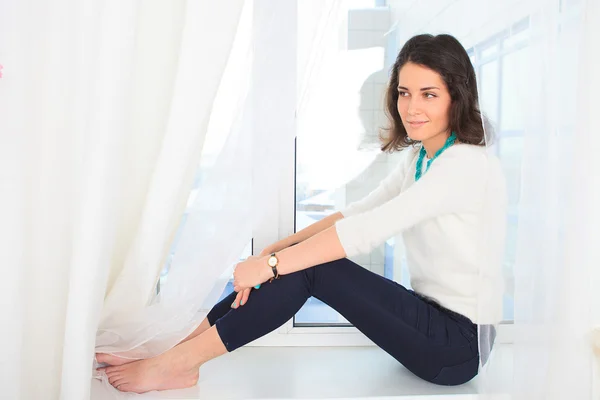 Chica sentada en un alféizar ventana — Foto de Stock