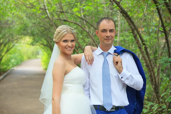 Bellissimi sposi che si abbracciano. I petali sotto forma di cuori che volano intorno a un nuovo sposo. Estate, amore, matrimonio . — Foto Stock