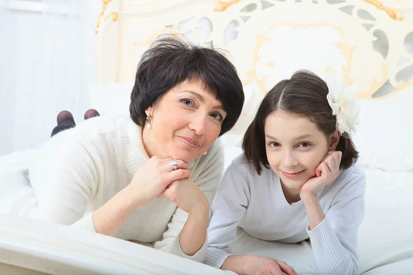 Mother and daughter lying in bed smiling to camera — Stock Photo, Image