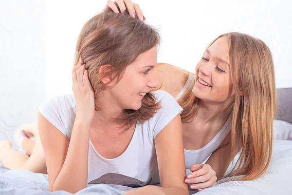 Two girls in bed eating cereal and laughing — Stock Photo, Image