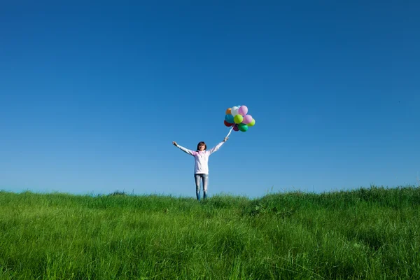 Feliz joven mujer sosteniendo globos de colores — Foto de Stock