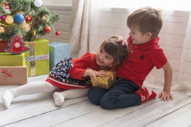 Oğlan, parlak güneşli bir odada bir kıza Noel hediyesi verir.
