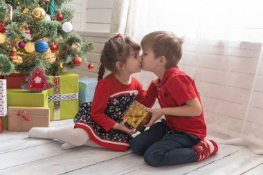 Oğlan, parlak güneşli bir odada bir kıza Noel hediyesi verir.