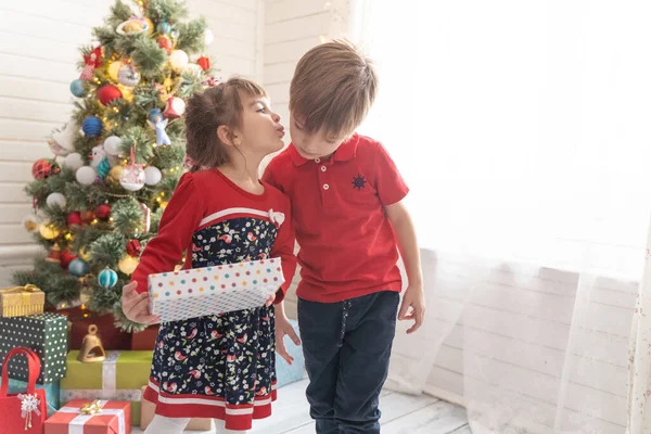 Oğlan, parlak güneşli bir odada bir kıza Noel hediyesi verir. — Stok fotoğraf