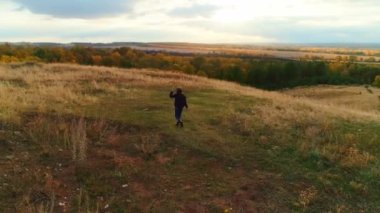Hava videosu. Sonbahar tarlasında yürüyüş yapan bir kız turist.
