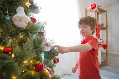 Evdeki Noel ağacını süsleyen küçük çocuk.