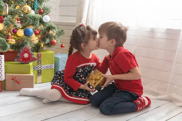 Oğlan, parlak güneşli bir odada bir kıza Noel hediyesi verir. — Stok fotoğraf