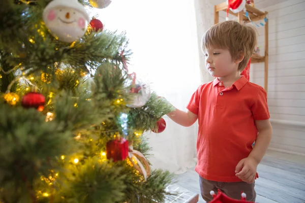 Evdeki Noel ağacını süsleyen küçük çocuk. — Stok fotoğraf