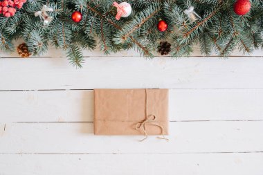 Noel arkaplanı, köknar dalları, peri ışıkları, hediye kutusu ve beyaz tahta üzerinde noel süslemeleri.