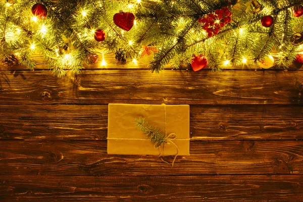 Christmas background, with fir branches, fairy lights, gift box and christmas decorations on white wooden plank — Stock Photo, Image